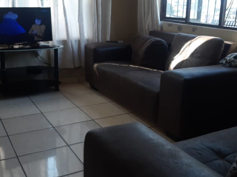 A living room featuring tiled flooring and a window with security bars, requiring minor cosmetic updates to the wall finishes.