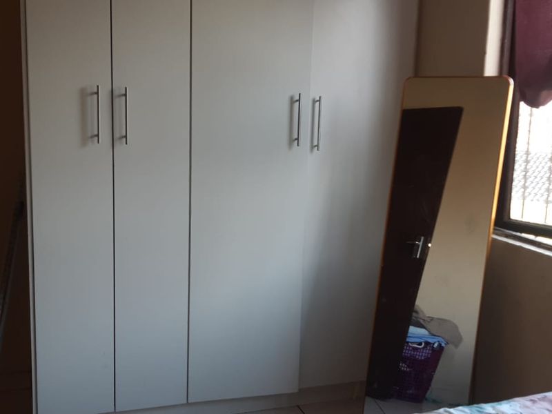 A bedroom featuring a built-in wardrobe and a window with security bars.