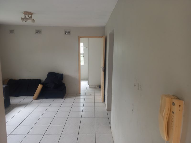 A living area featuring tiled flooring, an intercom system, and neutral wall finishes, providing a functional space ready for modernization.