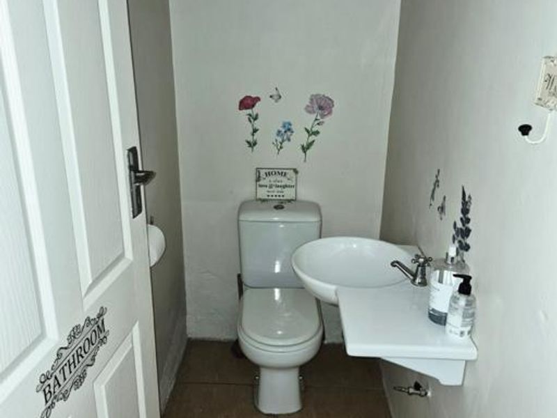 A compact guest bathroom featuring a standard toilet and a wall-mounted basin with tiled flooring.