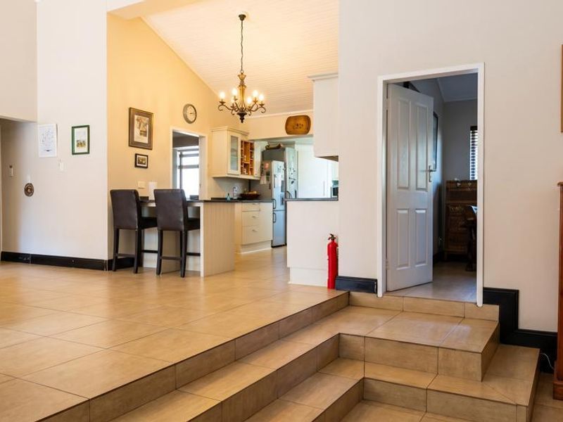 Spacious open-plan living area featuring tiled flooring, a raised floor section, vaulted ceilings, and a functional kitchen with a central island.
