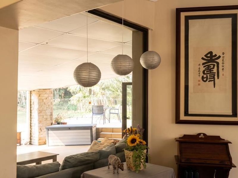 A bright living area featuring large sliding glass doors that open onto a covered patio with stone detailing and garden views.