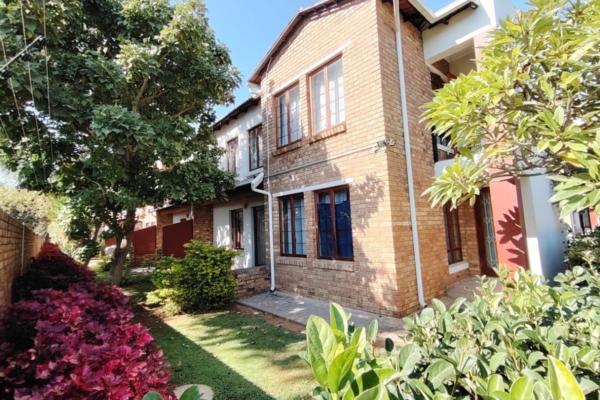 A well-maintained face brick exterior featuring timber window frames, a paved walkway, and established garden landscaping in a quiet residential setting.