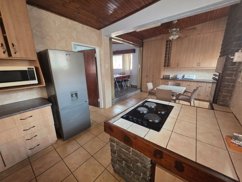 Open plan kitchen featuring tiled countertops, built-in cabinetry, and a timber ceiling, flowing into an adjacent dining area.