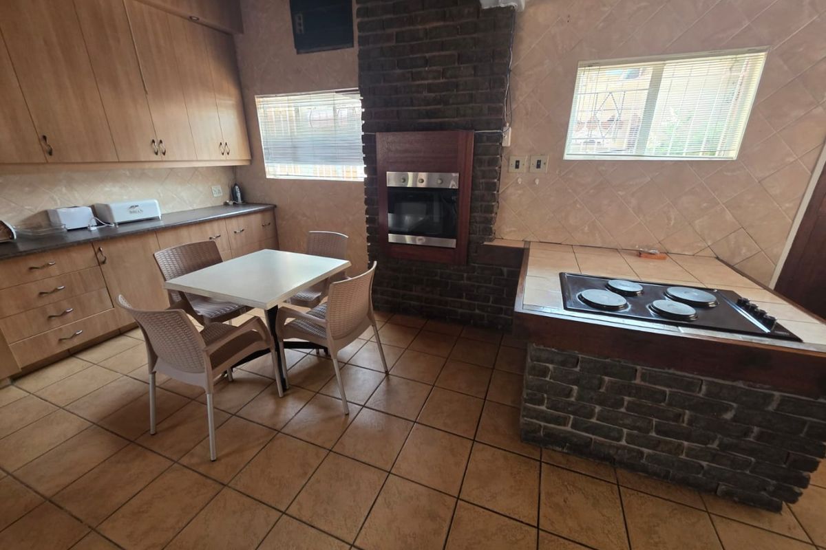A functional kitchen featuring built-in cabinetry, a brick-surround oven, and a tiled hob island, offering a traditional layout with potential for modern updates.