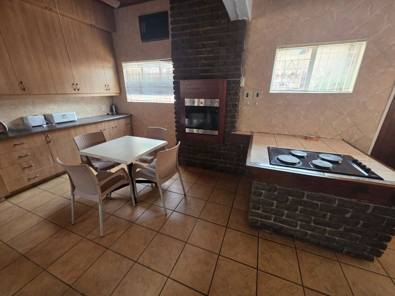 A functional kitchen featuring built-in cabinetry, a brick-surround oven, and a tiled hob island, offering a traditional layout with potential for modern updates.
