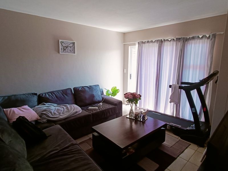 A living room featuring tiled flooring and a sliding glass door providing access to the exterior.