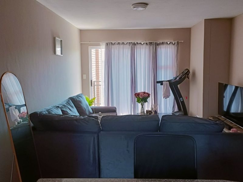 A living room area featuring a sliding glass door providing access to an outdoor space and a neutral wall finish.