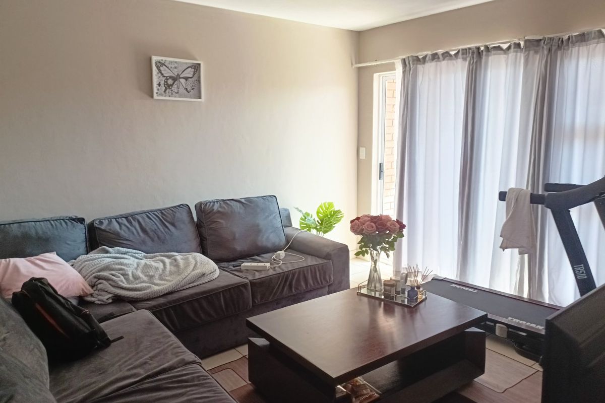 A comfortable living room featuring tiled flooring and a sliding glass door that provides access to the exterior.