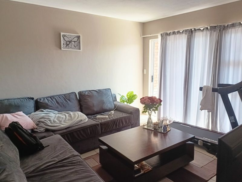 A comfortable living room featuring tiled flooring and a sliding glass door that provides access to the exterior.
