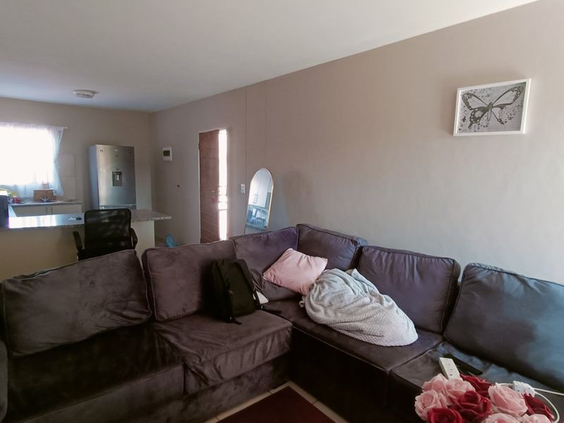 Open plan living area featuring a kitchen with a breakfast counter and tiled flooring, creating a functional and connected space.