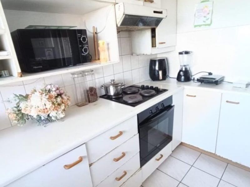 A functional kitchen featuring white cabinetry, a built-in oven, electric hob, extractor fan, and tiled flooring with a classic backsplash.