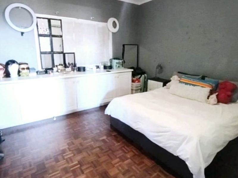 A bedroom featuring parquet flooring, built-in cabinetry, and coved ceilings, offering a functional space with potential for cosmetic updates.