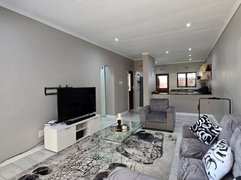 Open plan living area featuring tiled floors, recessed lighting, and a connected kitchen space with built-in cabinetry and countertops.