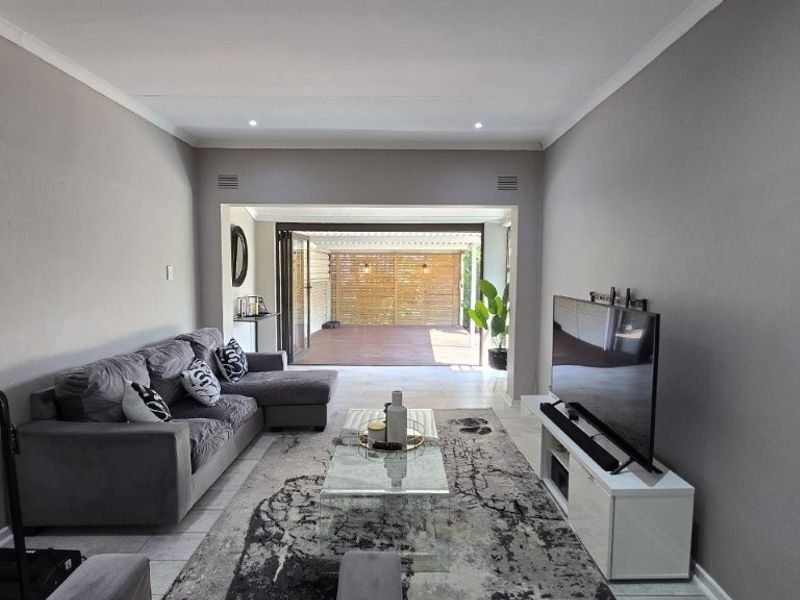 Spacious living room featuring neutral walls, tiled flooring, and large stacking doors that provide seamless access to the outdoor patio area.