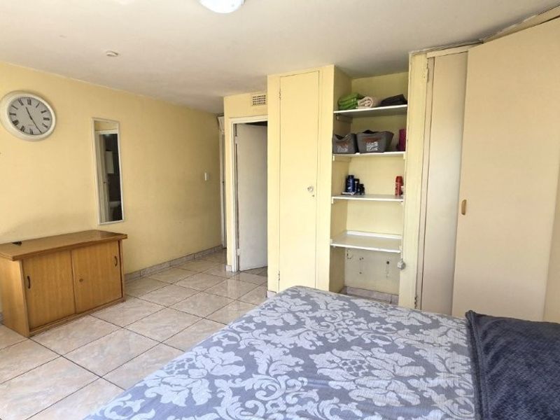 A bedroom featuring tiled flooring and built-in cupboard storage, offering a functional layout with potential for cosmetic updates.