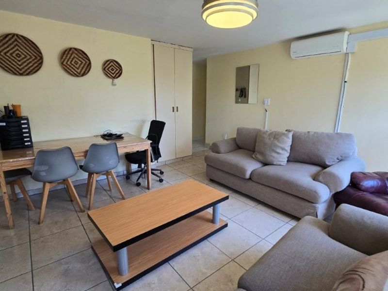 A functional living area featuring tiled flooring, built-in storage cupboards, and a wall-mounted air conditioning unit.