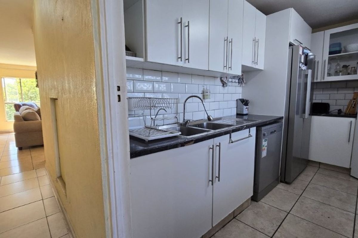 A functional kitchen featuring white cabinetry, subway tile backsplash, dark countertops, and tiled flooring, providing a practical workspace for daily meal preparation.