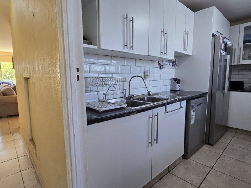 A functional kitchen featuring white cabinetry, subway tile backsplash, dark countertops, and tiled flooring, providing a practical workspace for daily meal preparation.