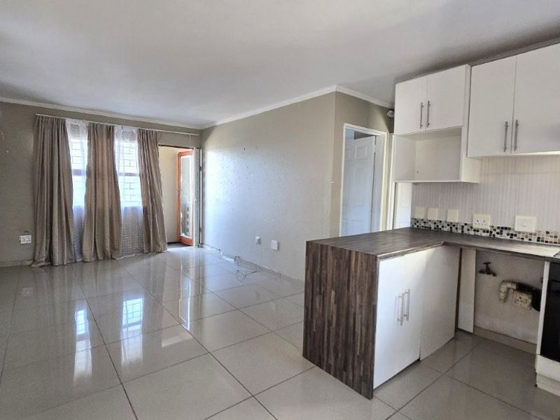 Open-plan living area featuring tiled floors and a functional kitchen with built-in oven, extractor fan, and modern cabinetry.