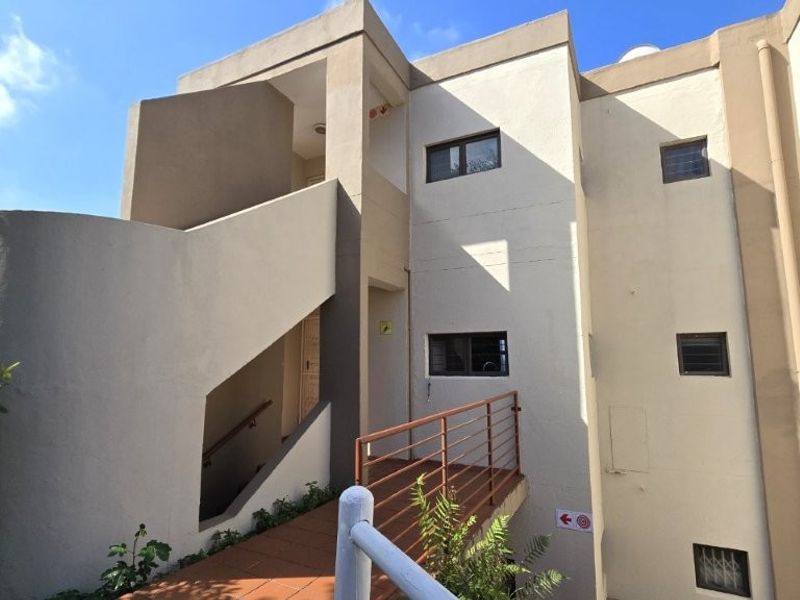 Exterior view of a multi-level townhouse featuring a concrete staircase, tiled walkway, and security windows on the facade.