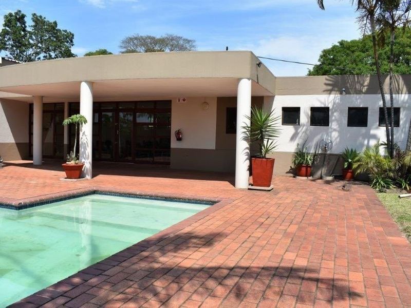 Outdoor pool area featuring a brick-paved patio and a covered veranda, providing a functional space for outdoor relaxation and entertainment.