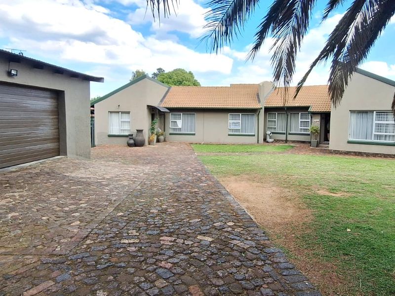 Front view of a single-story house featuring a cobblestone driveway, attached garage, and a well-maintained lawn area.