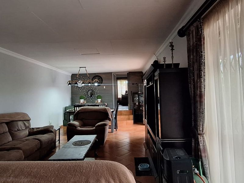 Spacious open-plan living and dining area featuring tiled flooring, coved ceilings, and large sliding glass doors providing access to the exterior.