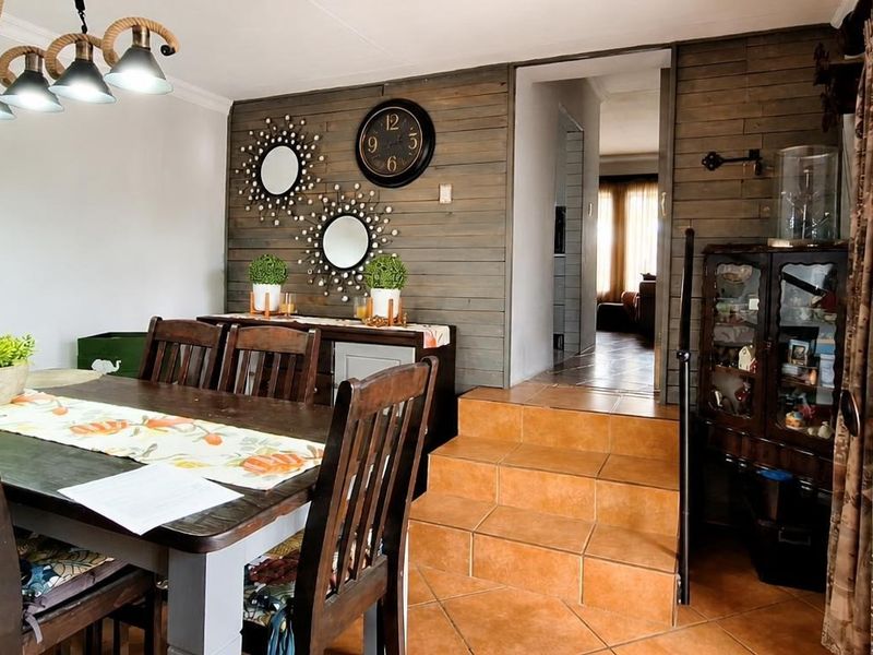 Dining area featuring a timber-clad accent wall, ceramic floor tiles, and a raised transition to the adjacent living space.