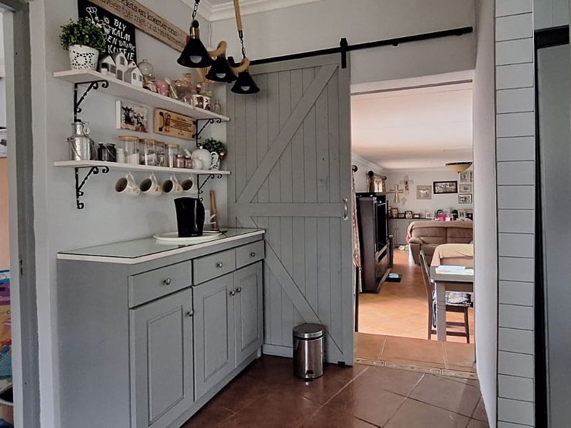 A functional scullery area featuring built-in cabinetry, a sliding barn door, and tiled flooring, providing a convenient transition space between rooms.