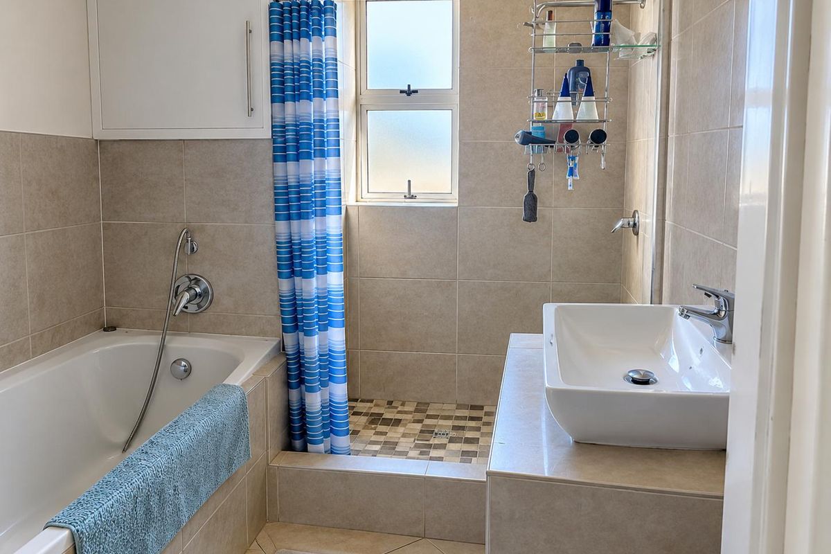 A functional bathroom featuring a built-in bathtub, a separate shower area with tiled finishes, and a modern vessel sink vanity.