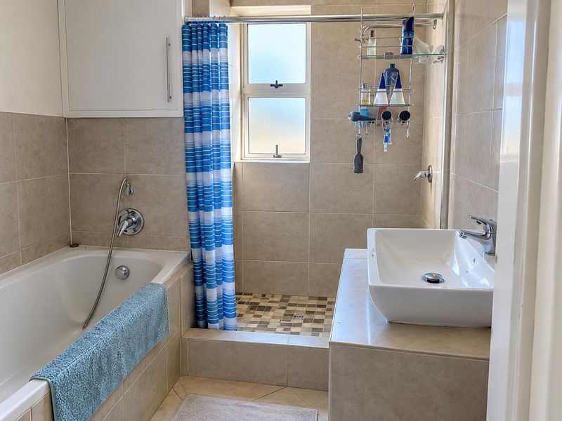 A functional bathroom featuring a built-in bathtub, a separate shower area with tiled finishes, and a modern vessel sink vanity.
