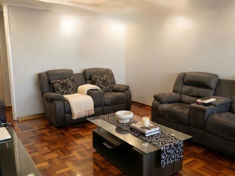 A comfortable living room featuring classic parquet flooring and recessed ceiling lighting, providing a warm and inviting atmosphere for relaxation.