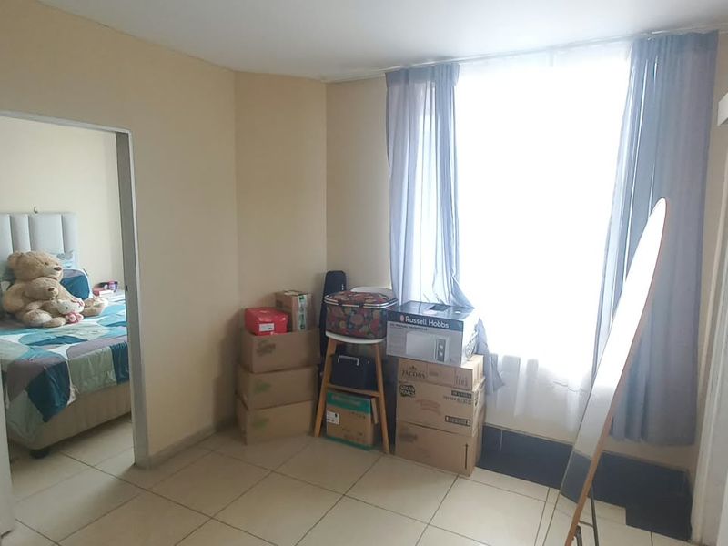 A bedroom featuring tiled flooring, a sliding door entrance, and a built-in cupboard, offering a functional layout with natural light.