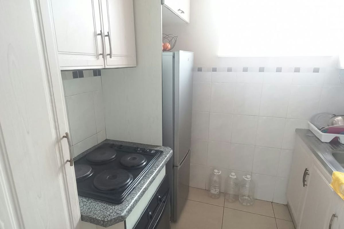 Compact kitchen featuring built-in cabinetry, granite countertops, a tiled backsplash, an electric hob, and a stainless steel sink.