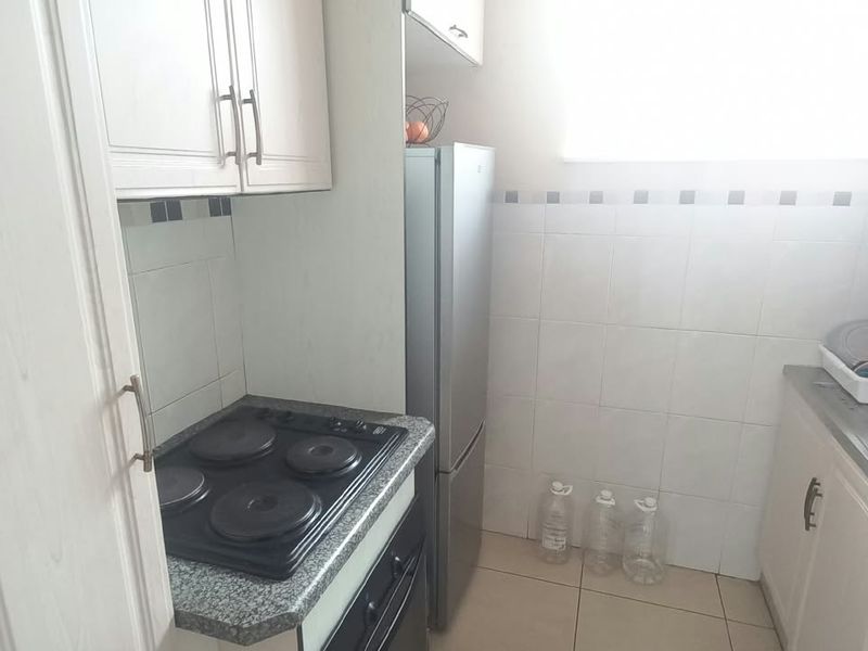 Compact kitchen featuring built-in cabinetry, granite countertops, a tiled backsplash, an electric hob, and a stainless steel sink.