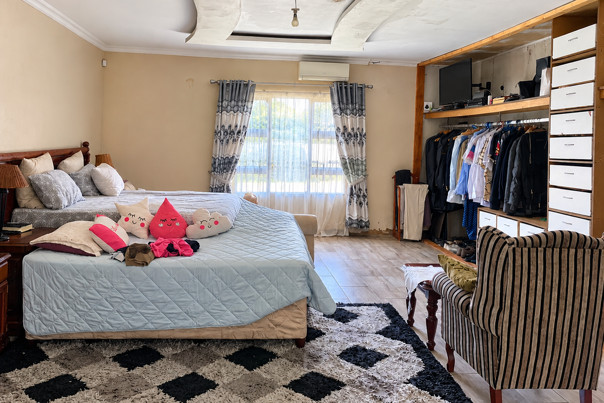 Spacious bedroom featuring a built-in open wardrobe, recessed ceiling detail, and split-system air conditioning, offering a functional layout with tiled flooring.