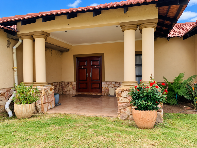 Front entrance featuring a covered porch with decorative columns, stone cladding accents, and a solid wood double door entry.