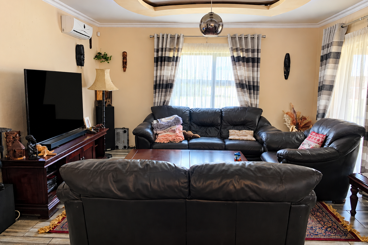 A comfortable living room featuring a decorative recessed ceiling, tiled flooring, and a wall-mounted air conditioning unit.