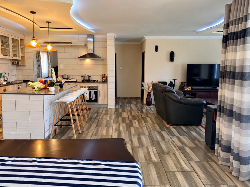 Spacious open-plan living area featuring a modern kitchen with a central island, built-in appliances, and contemporary tiled flooring throughout.