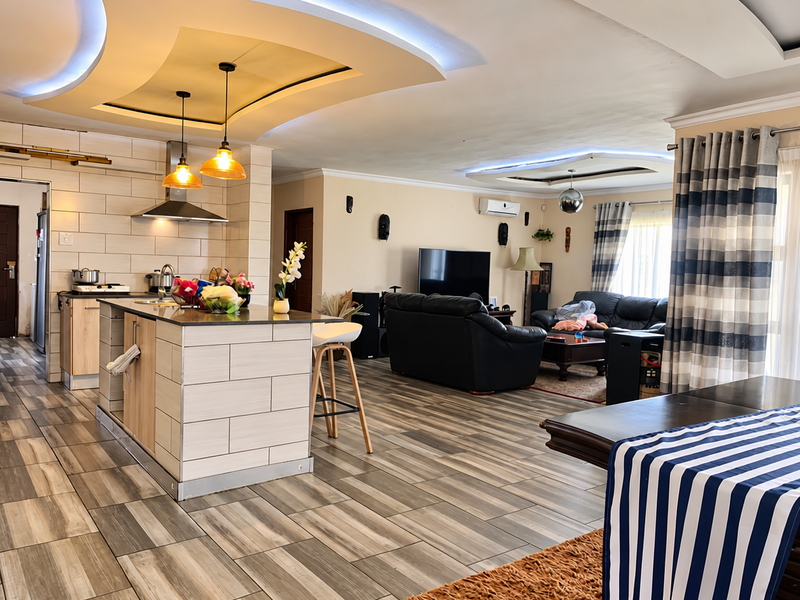 Spacious open-plan living area featuring a modern kitchen island, contemporary tiled flooring, and recessed ceiling lighting with integrated air conditioning.