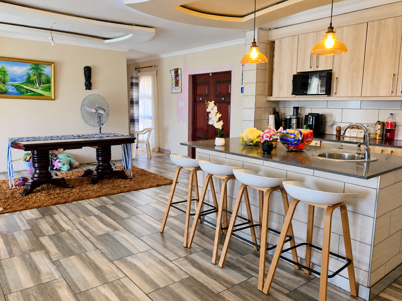 Open plan living and kitchen area featuring a central island with breakfast bar, modern cabinetry, and tiled flooring throughout.