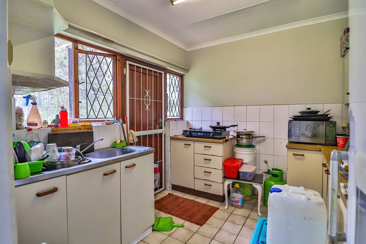 A functional kitchen featuring tiled flooring, a stainless steel sink, and built-in cabinetry, offering potential for modernization and cosmetic updates.