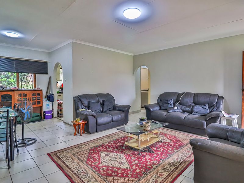 Spacious open-plan living area featuring tiled flooring, neutral walls, and arched doorways leading to adjacent rooms.
