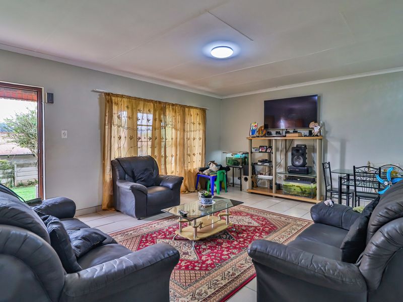 A spacious living room featuring tiled flooring and a glass sliding door providing access to the exterior.