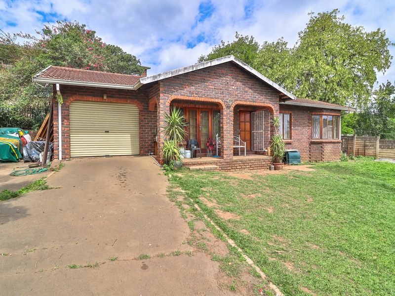 Front view of a single-story brick house featuring a tiled roof, a single garage with a roller door, and a covered entrance porch.