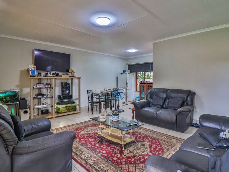 Spacious open-plan living and dining area featuring neutral wall finishes, tiled flooring, and recessed ceiling lighting.