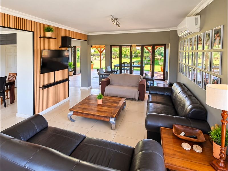 Spacious living room featuring a timber slat feature wall, tiled flooring, and large sliding glass doors that provide seamless access to the outdoor patio area.