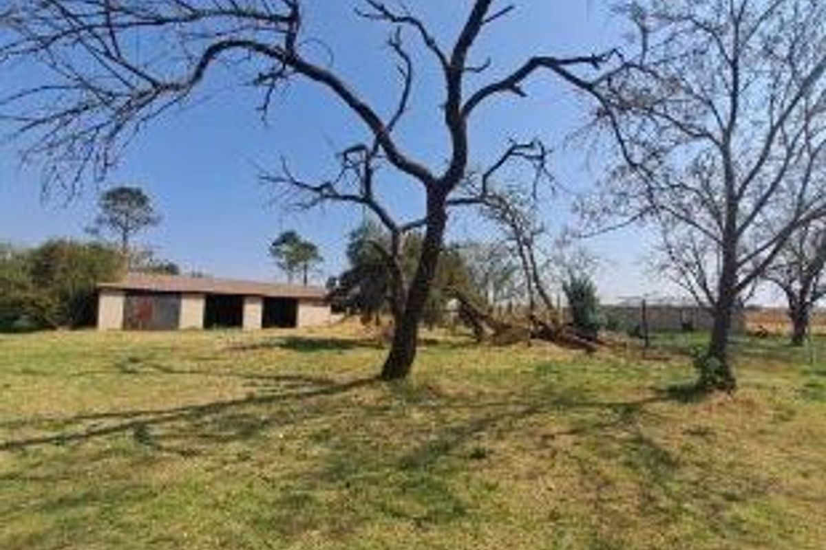 A view of the farm grounds featuring an outbuilding and mature trees on the property.