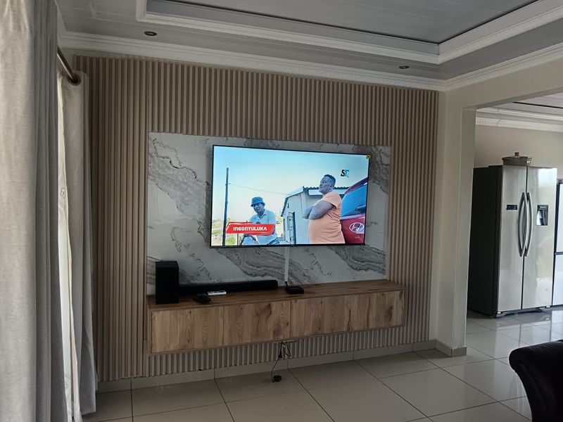 Modern living room featuring a stylish slatted timber and marble-look feature wall with a floating media console and recessed ceiling lighting.